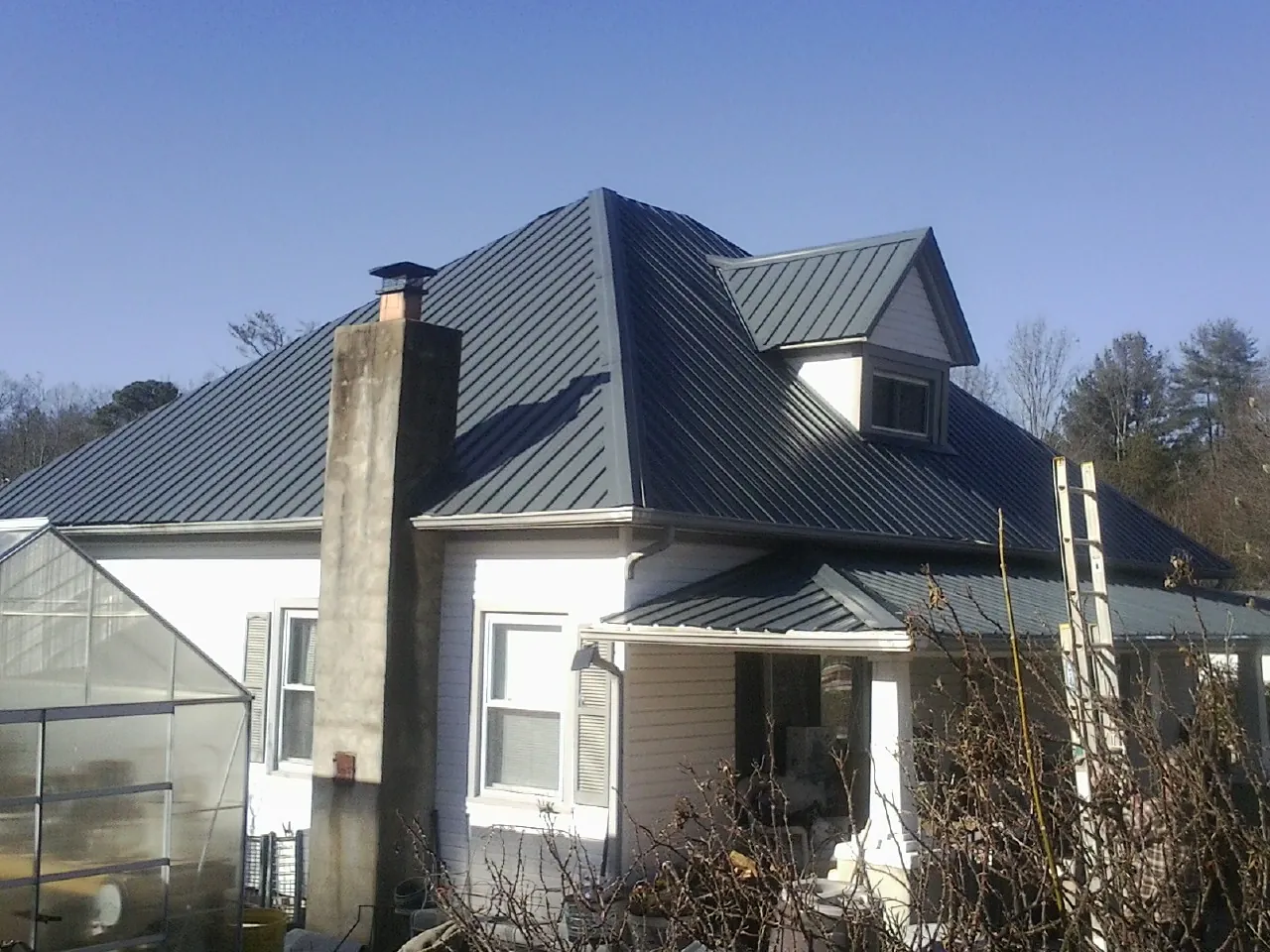 Dark blue standing seam metal roof on a white farmhouse with dormer — Slate & Tile Roof Repair by Roofing Brothers in Markleysburg