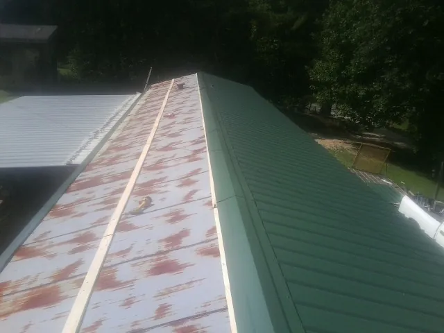 Old rusted panels beside newly installed green metal roofing — Wind Damage Roof Repair by Roofing Brothers in Markleysburg
