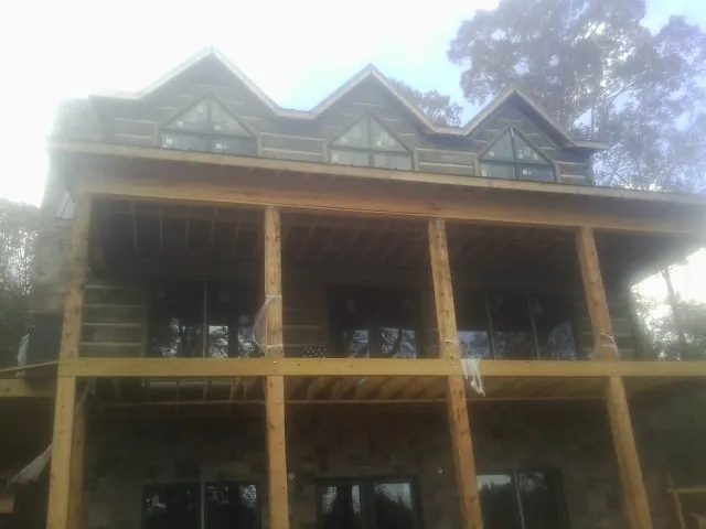 Dormers and porch framing on a large log home under construction — Roof Coating work by our crew in Markleysburg