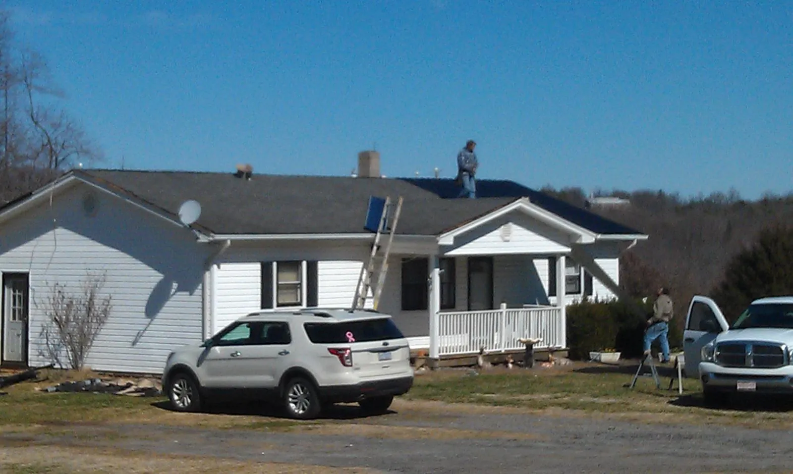 Roofers stripping shingles from a white ranch house roof in Markleysburg