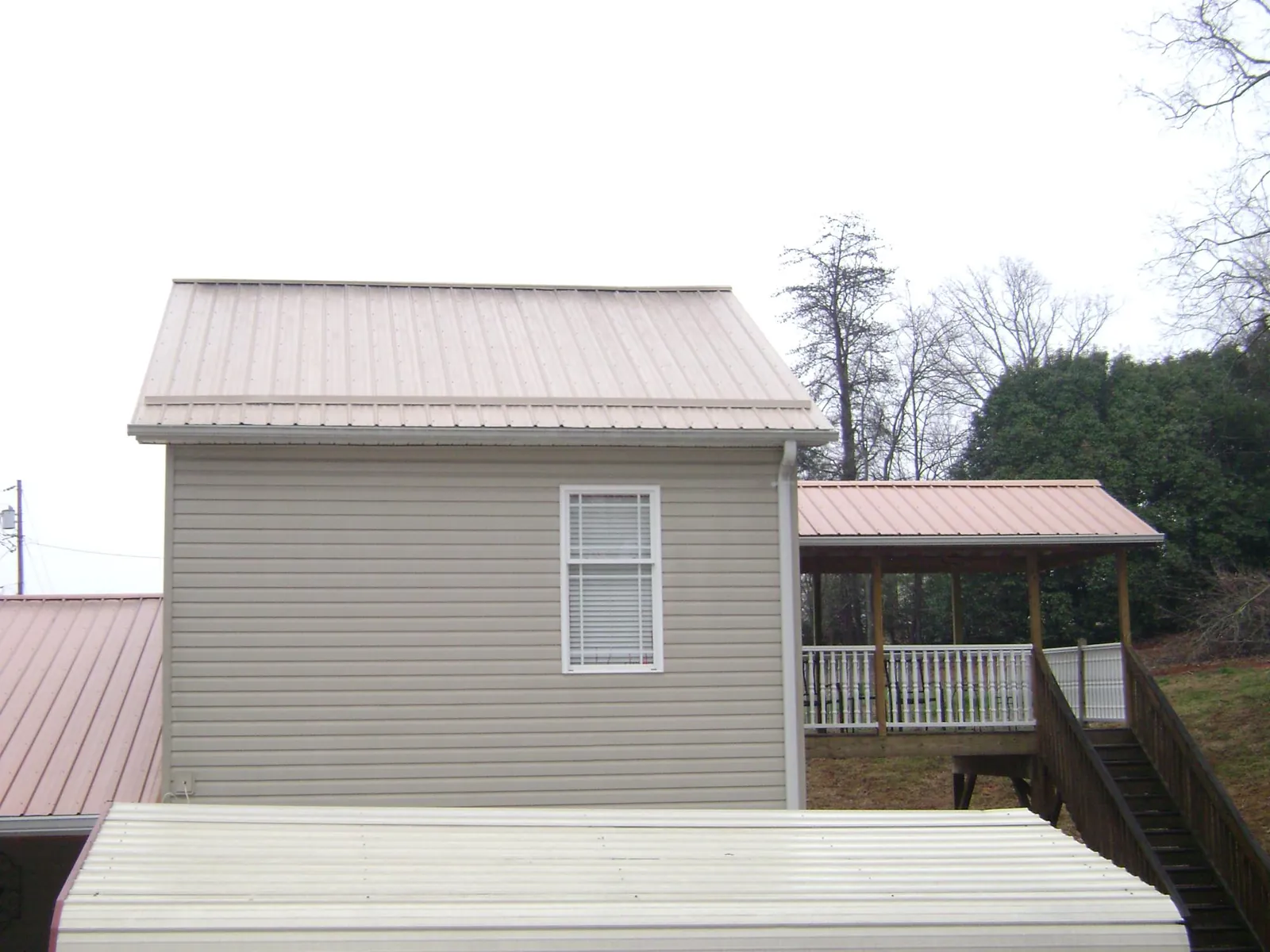 Tan metal roofs on a two story addition and attached porch, from a Roof Replacement job in Markleysburg