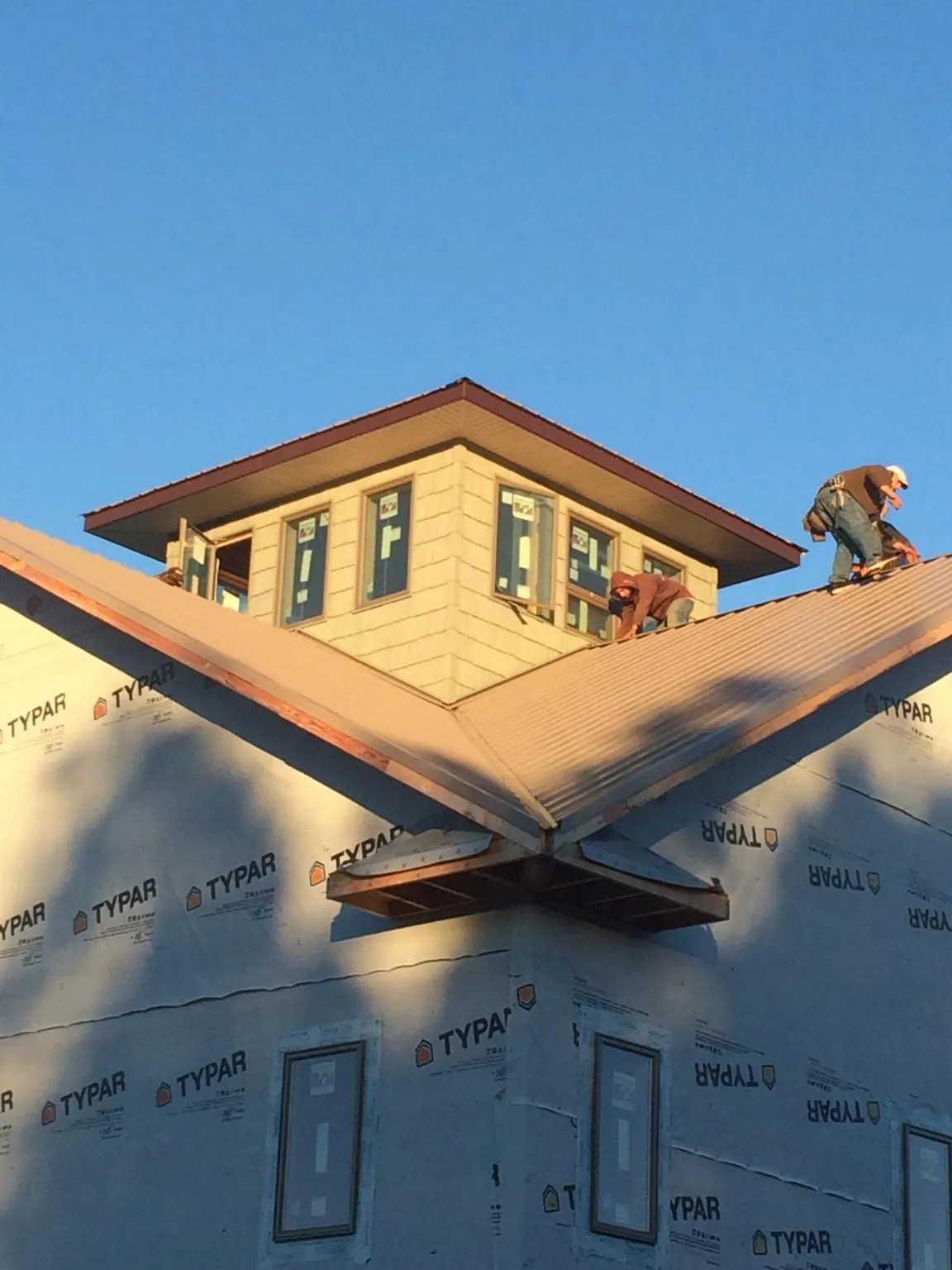 Roofers working around a rooftop cupola on a new metal roof at sunset — Roof Waterproofing in Markleysburg by Roofing Brothers